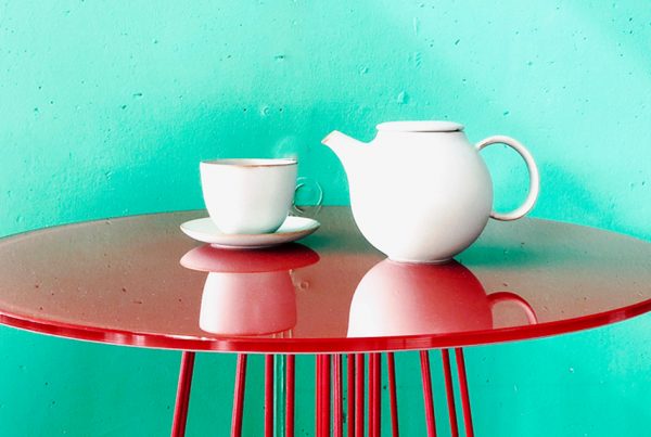 Teekrug auf rotem Tisch vor grüner Wand
